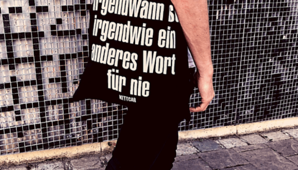 Mann mit Tasche auf der steht "Irgendwann ist irgendwie ein anderes Wort für nie"