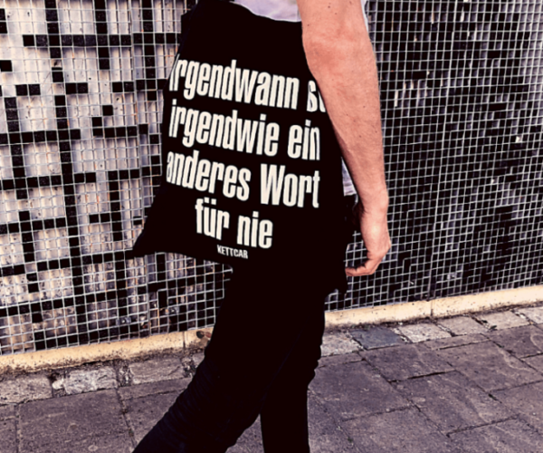 Mann mit Tasche auf der steht "Irgendwann ist irgendwie ein anderes Wort für nie"