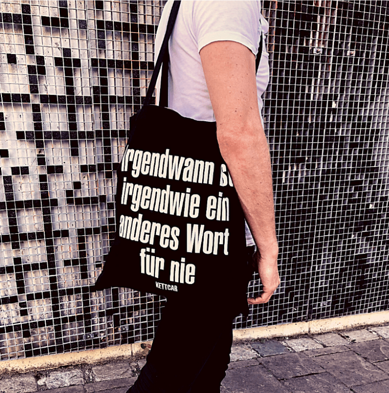 Mann mit Tasche auf der steht "Irgendwann ist irgendwie ein anderes Wort für nie"