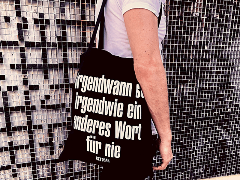 Mann mit Tasche auf der steht "Irgendwann ist irgendwie ein anderes Wort für nie"